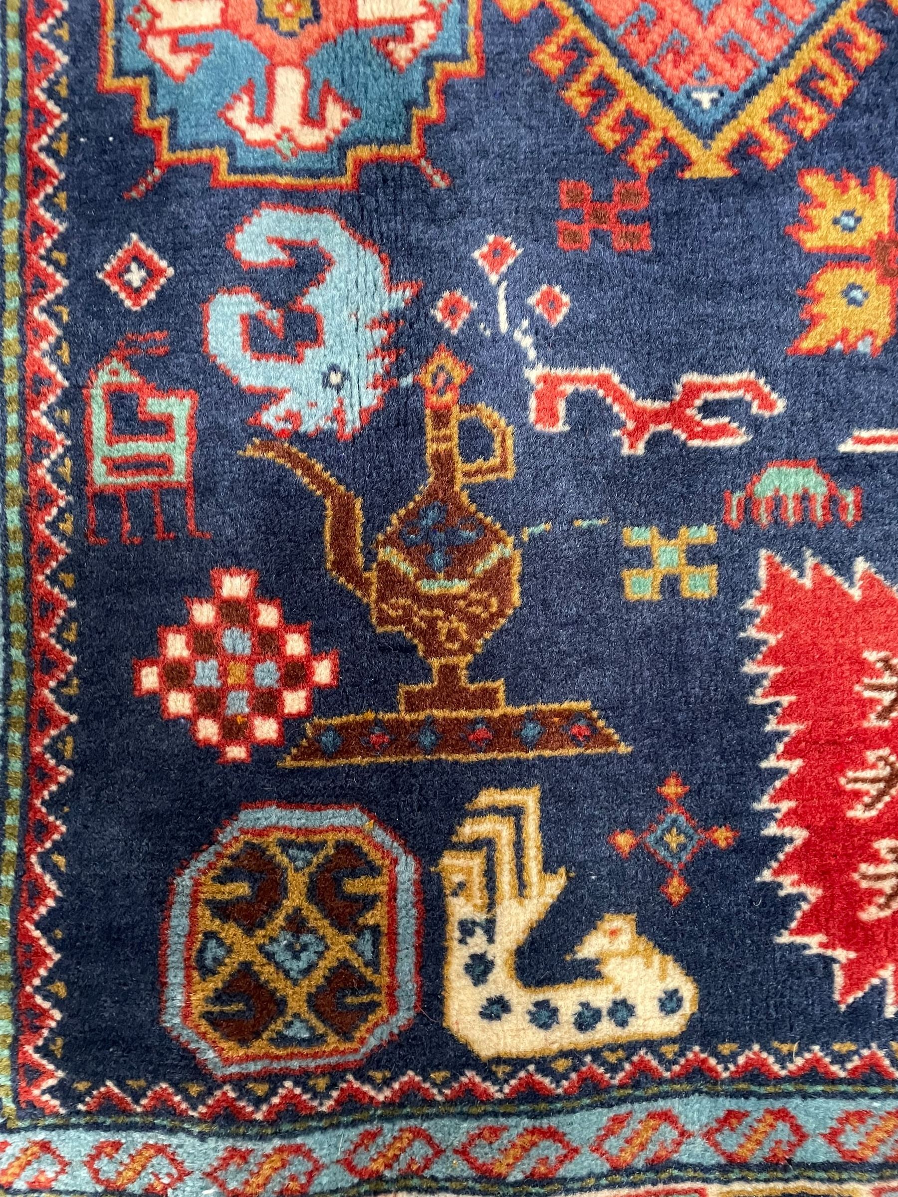 Persian Ardabil indigo ground rug, four interconnected lozenge medallions surrounded by ewer, bird, dragon, camel and geometric motifs, hooked border within guard stripes 
