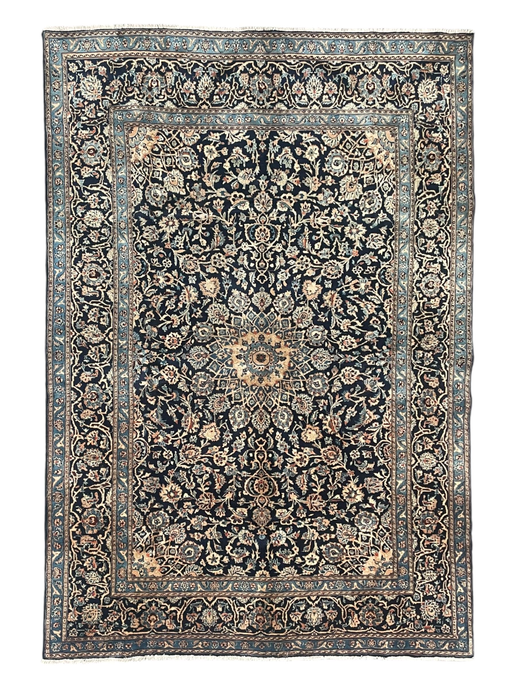 Persian Kashan indigo ground rug, the rosette medallion decorated with projecting palmettes, on a field of swirling leafy branches and decorated with further palmettes, the scrolling border with repeating stylised plant motifs, within floral pattern guard stripes