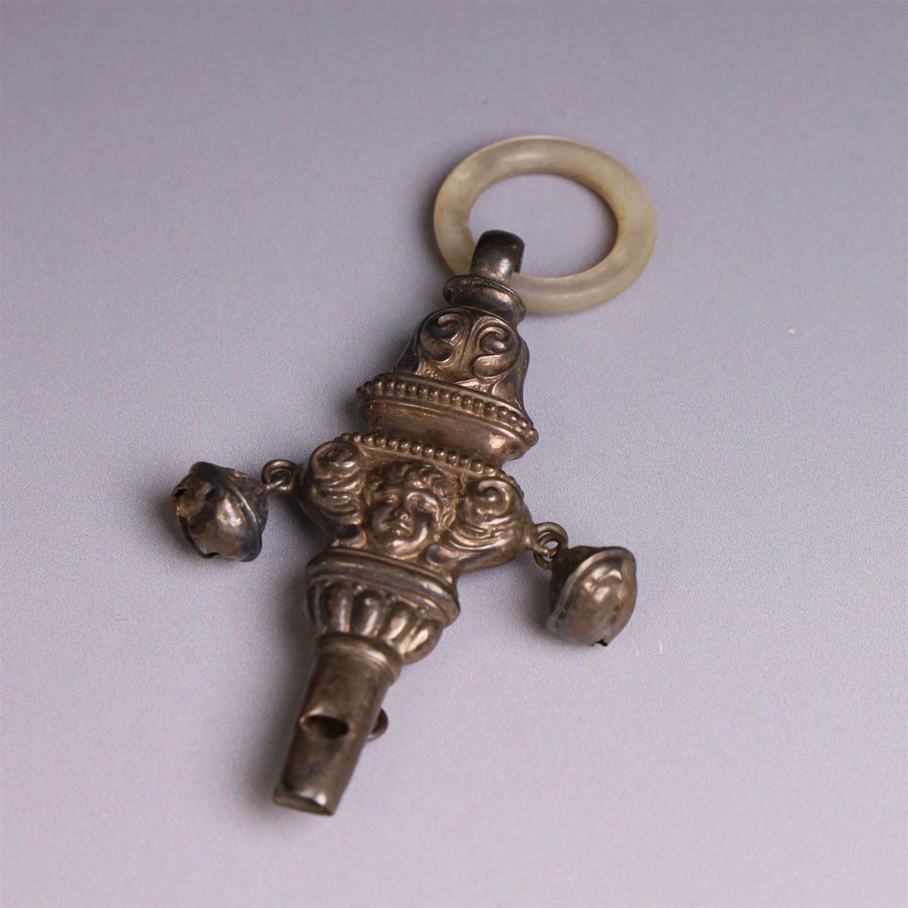 Edwardian silver rattle, embossed with putti and scrolling decoration, with whistle, bells and mother of pearl teething ring, hallmarked Crisford & Norris Ltd, Birmingham 1906, L10cm