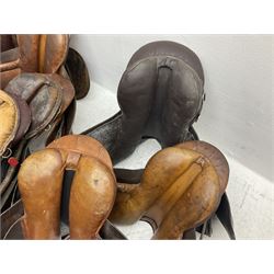Collection of eight saddles, mainly havana leather, some with stirrups and leathers 