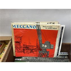 Meccano - large quantity of loose parts including various plates and strips, flanged plates, pulleys, axle rods and crank handles, wheels and tyres, gear wheels, brackets, nuts & bolts, various manuals; predominantly red and green; some in compartmentalised wooden trays