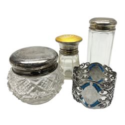 Three glass dressing table jars with silver covers, to include an example with yellow guilloche enamel and silver cover, hallmarked Birmingham 1923, plus an Edwardian silver napkin ring, approximate weighable silver 44.1 grams