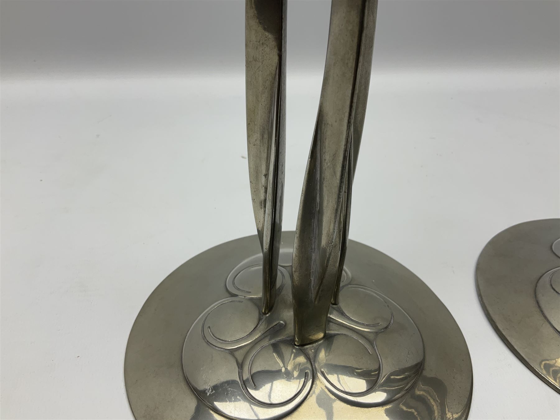 Archibald Knox (1864-1933) for Liberty & Co, pair of Tudric pewter candlesticks, the bud shaped sockets raised upon three angular fin supports and a slightly domed circular base with cast stylised foliate decoration, each stamped beneath Tudric 0223, H30cm