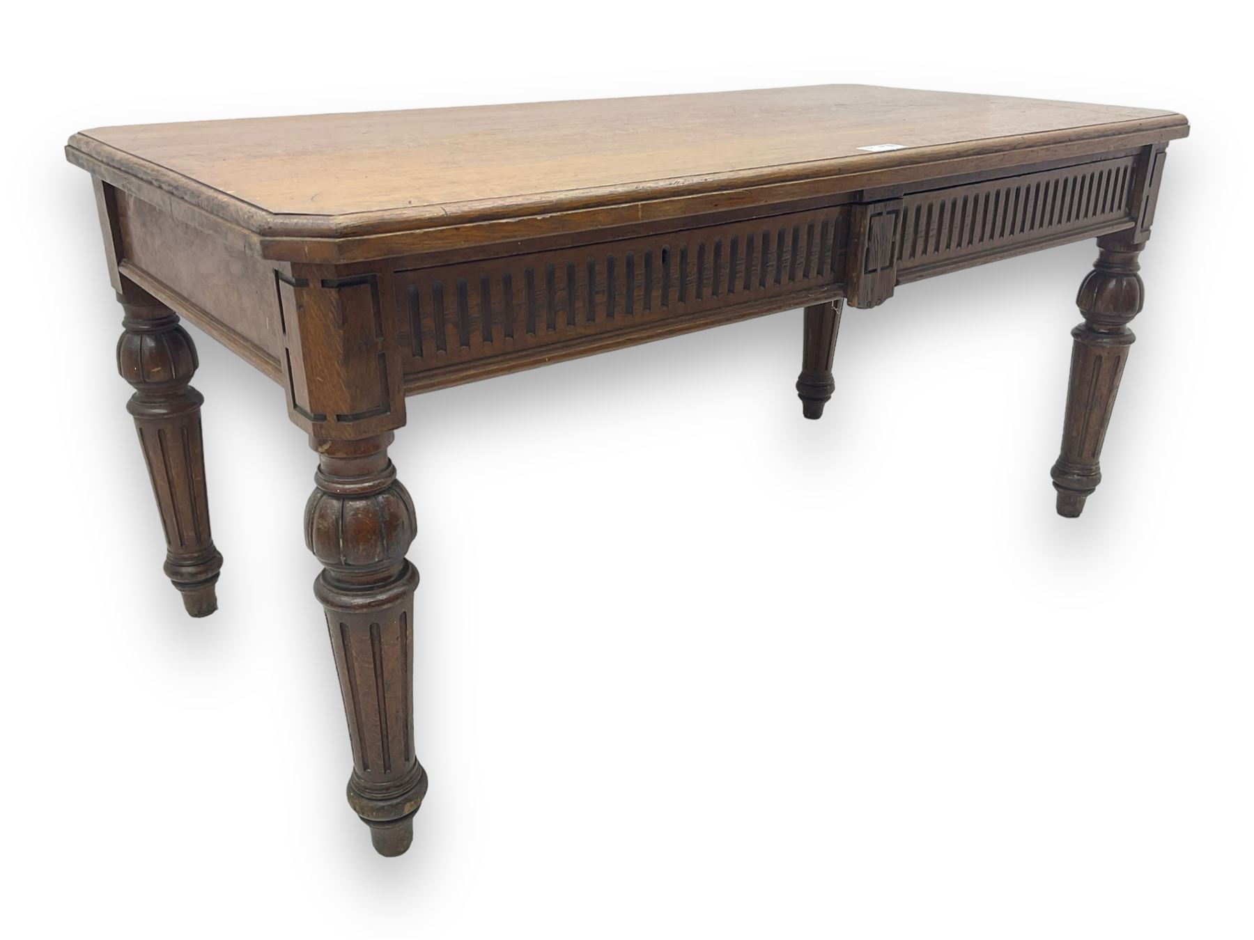 Late 19th century oak library table, moulded rectangular top with canted corners, fitted with two frieze drawers with fluted facias, on lobe carved and fluted turned supports 