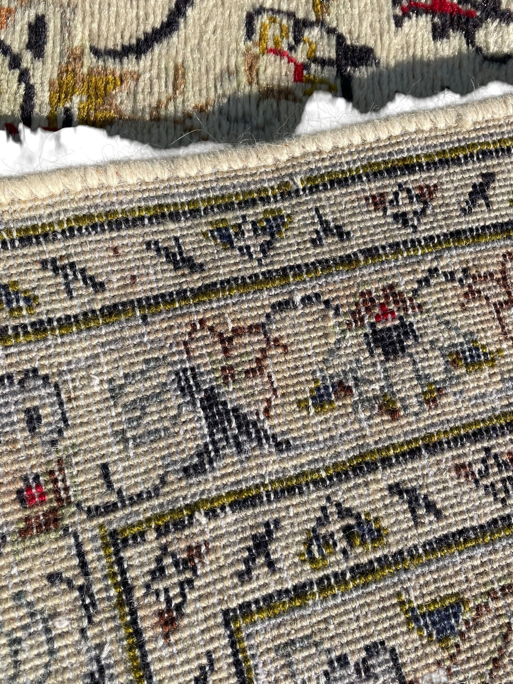 Persian Kashan ivory ground carpet, central medallion decorated with sixteen arranged palmette motifs, within a field decorated with swirling leafy branches and stylised plant motifs, the main border decorated with matching swirling pattern, within floral pattern guard stripes 