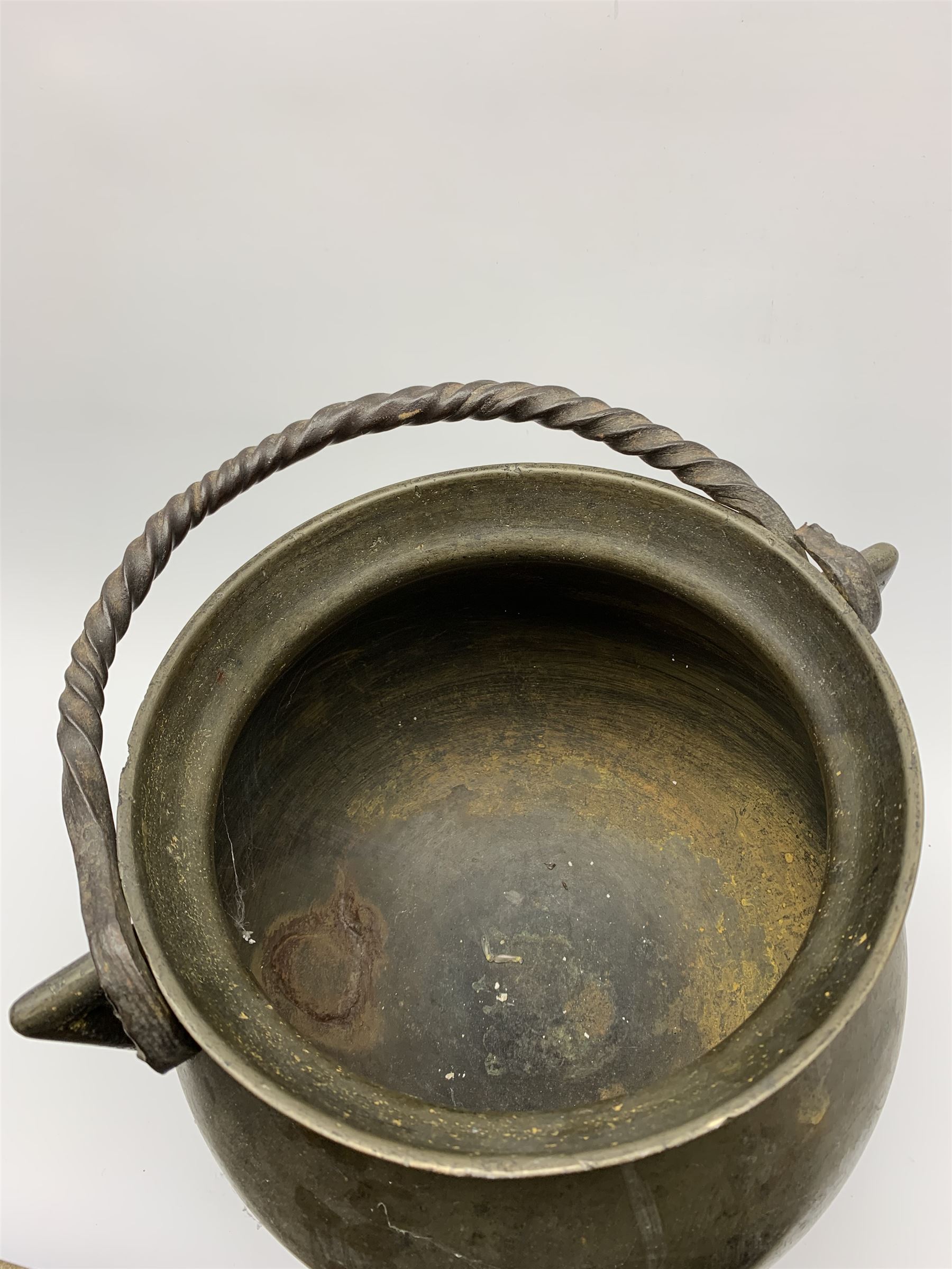 17th century bronze cauldron, probably German or Austrian, of bellied form with twin angular handles supporting a twisted handle, upon three splayed zoomorphic bearded mask feet, not including handle H30cm, rim D22cm