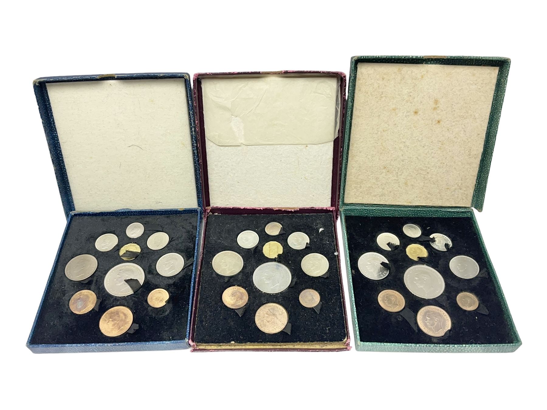 Three King George VI 1951 'Festival Of Britain' specimen coin sets, each comprising farthing to crown coins, housed in maroon, green and blue dated boxes 