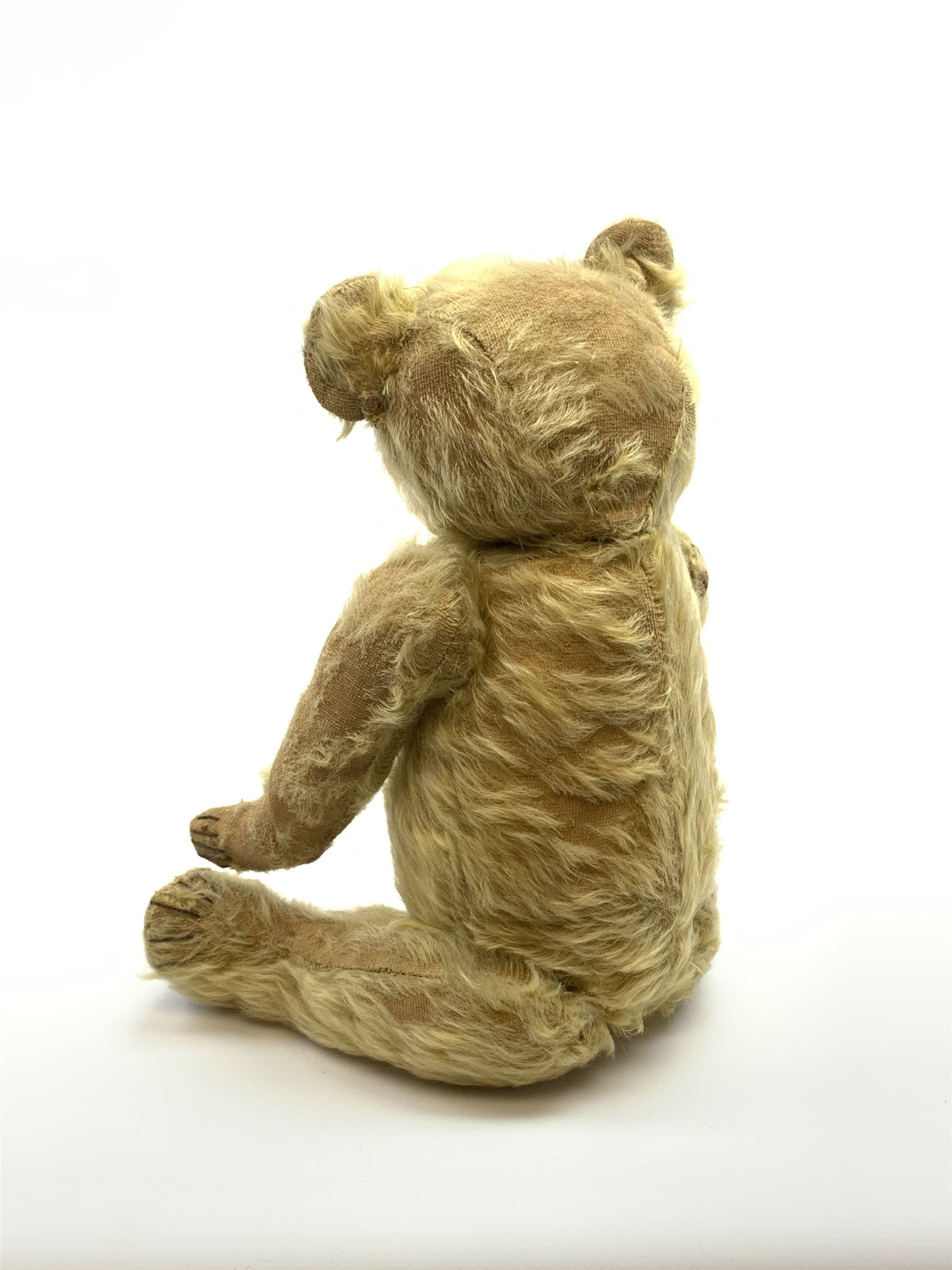 1930s teddy bear, possibly Farnell, with wood wool filled blond mohair body, the revolving head with original clear glass eyes, shaved muzzle with vertically stitched nose and mouth and jointed limbs with five-stitch claws H18.5