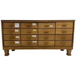 Early 20th century oak framed haberdashery shop counter, veneered top with glazed front and sides, fitted with sixteen graduating drawers with oak fronts and handles, raised on shaped supports