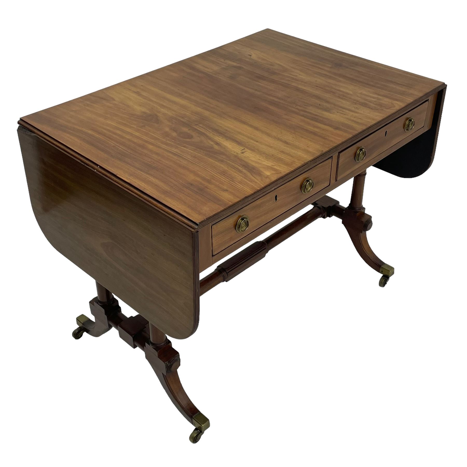 George III mahogany sofa table, rectangular drop-leaf top with reed moulded edge and rounded corners, fitted with two frieze drawers and two opposing false drawers, quadruple collar turned pillar supports on turned and block platforms, splayed and moulded supports with brass cups and castors 