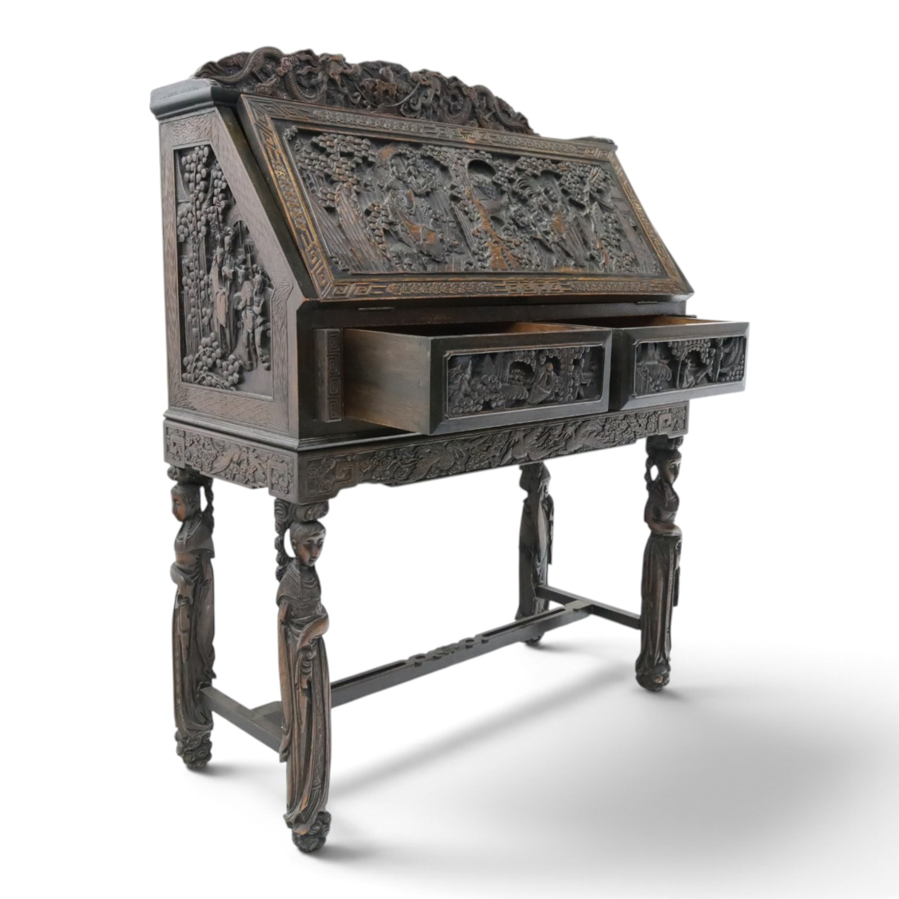 Early 20th century Chinese export carved hardwood writing bureau, the sloped fall front deeply carved with a narrative figural scene beneath pine and prunus trees, above a pair of rectangular carved panels, the shaped crest rail with entwined dragons, interior fitted with pigeonholes and a central drawer, on figural front supports with shaped stretcher