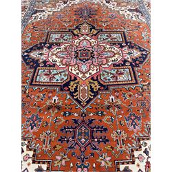 Large Persian carpet, the geometric and stylised floral medallion on rust ground field decorated with stylised plant motifs, guarded ivory border with repeating pattern