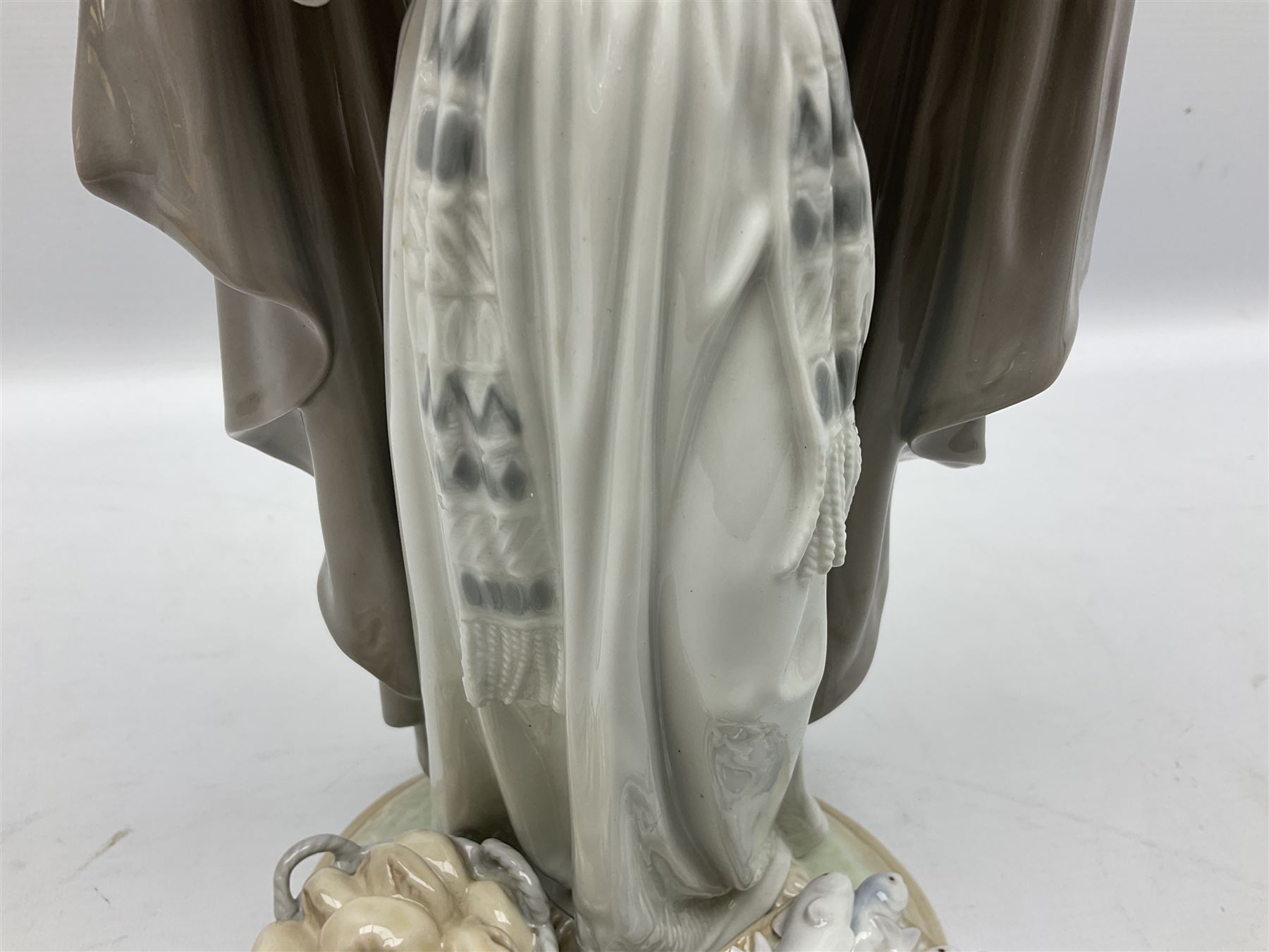 Lladro figure, The Loaves and Fishes, modelled as Jesus Christ with arms raised standing beside a basket of loaves and a basket of fish, sculpted by Salvador Furió, with original box, no 5896, year issued 1992, year retired 1997, H35cm