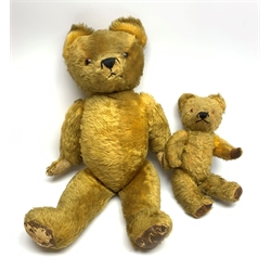  Mid-20th century English teddy bear, the plush covered body with inoperative growler mechanism, applied eyes, stitched nose and mouth and jointed limbs with rexine patches, traces of Made in England label to foot, H65cm together with another similar smaller teddy bear H37cm (2)  