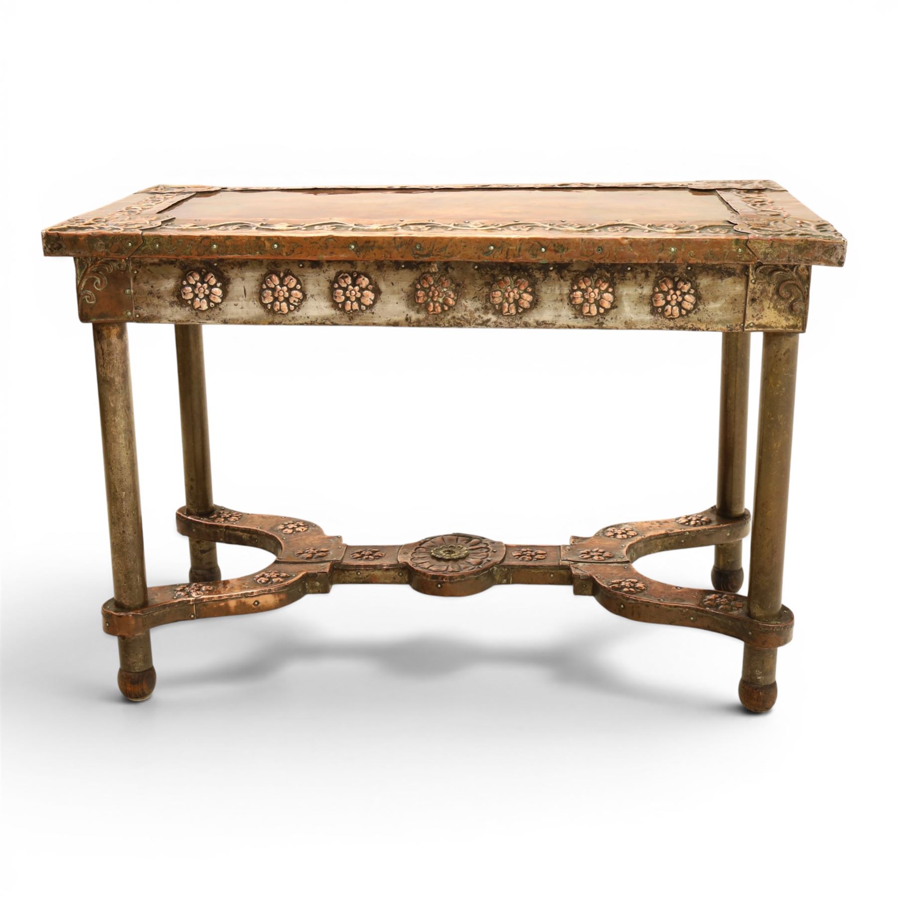 Arts and Crafts copper mounted coffee table, rectangular top with embossed foliate border and stylised corner motifs, studwork detail, on cylindrical supports united by pierced shaped stretcher with applied flowerhead bosses