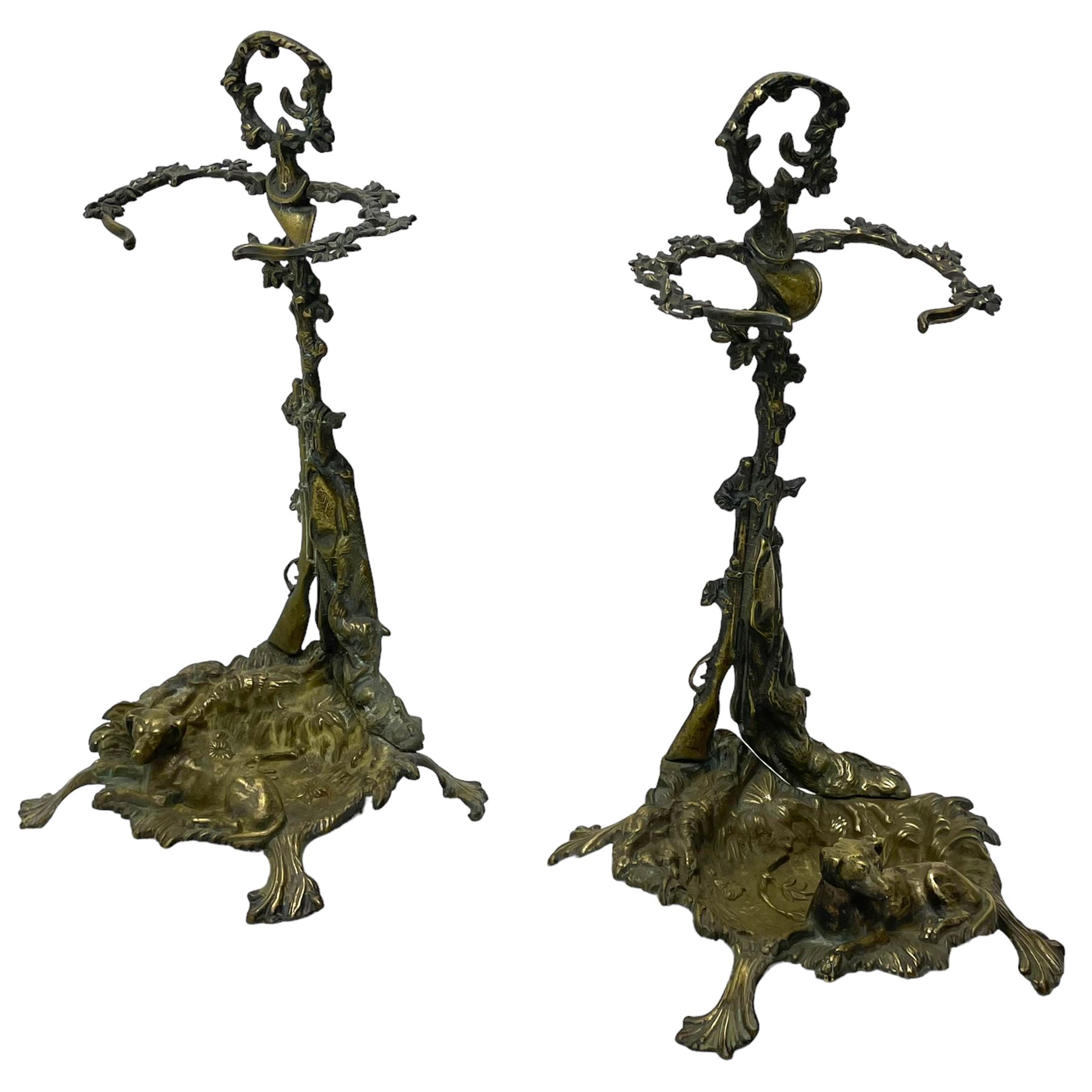 Pair of cast brass hallway umbrella or stick stands, in the form of a tree decorated with trailing flowering foliage branches, the stem with hunting horn over leaning shotgun, shaped naturalist tray base with hunting hound and out splayed foliate cast feet 