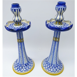  Gouda for Liberty & Co. pair pottery candlesticks of lobed tapering form with circular drip trays and double gourd shaped sconces, painted in underglaze blue with stylized motif and yellow bandings, H38.5cm    