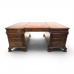 George III style large mahogany reverse breakfront partners desk, red tooled leather writing surfaces crossbanded and moulded edges, flanked by ring-turned cluster columns three frieze drawers with brass swan neck handles, raised on large pedestals with faux drawer fronted cupboard and three graduated drawers, supported on carved ogee feet decorated with C-scrolled and acanthus leaves