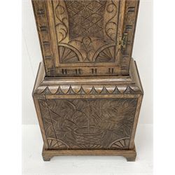 19th century carved oak longcase clock, projecting cornice over guilloche carved frieze, square brass dial with silvered Roman chapter ring and calendar aperture, decorated with ornate mask cast spandrels, the trunk door and base carved with potted plant, twin train driven eight day movement striking on bell