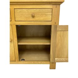 Contemporary light oak bookcase display cabinet, fitted with  two glazed doors enclosing two shelves, above two drawers and cupboards