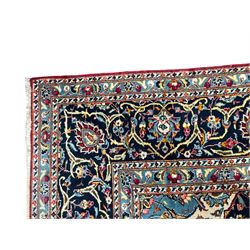 Persian Kashan crimson ground carpet, the central pole medallion decorated with flower heads, surrounded by trailing leafy branches and palmettes, scrolling border decorated with further palmettes, within floral pattern guard stripes 