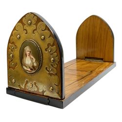 Victorian olive wood book slide, the arched supports with scrolling brass mounts enclosing KPM type porcelain plaques depicting a young female figure in diaphanous veil holding an oil lamp, her arm leaning upon a stone column, retracted W36cm, extended W56cm