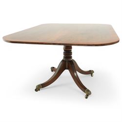 Early 19th century Sheraton style mahogany and rosewood pedestal breakfast table, the rectangular top with rounded corners and crossbanded edge, raised on a turned column support with reeded detail, terminating in four splayed legs with brass caps and castors