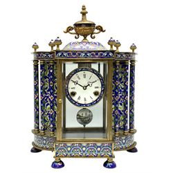A decorative 20th  century Chinese mantle clock with blue cloisonné decoration and four bevelled glass panels, flat pediment surmounted by four finials and an ornamental central urn, matching full length pillars to the sides with a conforming plinth on raised feet, 8-day striking movement striking the hours and half hours on a coiled gong, dial with Roman numerals, five-minute Arabic’s, minute markers and matching steel trefoil hands, visible pendulum with painted decoration.
