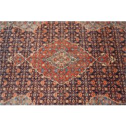 Persian indigo ground Herati rug, the busy field with a central lozenge pole medallion surrounded by repeating Herati motifs, within a shaped spandrel border the crimson guard band decorated with repeating palmette motifs
