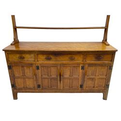 Yorkshire Oak 'Kingpost' - oak dresser, raised two heights plate rack, the base with rectangular adzed top over three drawers, central double cupboard and flanking single cupboards, enclosed by panelled doors, the plate rack and base each carved with kingpost signature, by Robert Ingham, Burton Leonard, Harrogate