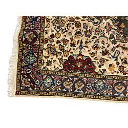 Persian ivory ground rug, central green floral pole medallion within a field decorated by scrolling foliate patterns, the guarded border with repeating palmettes and floral designs