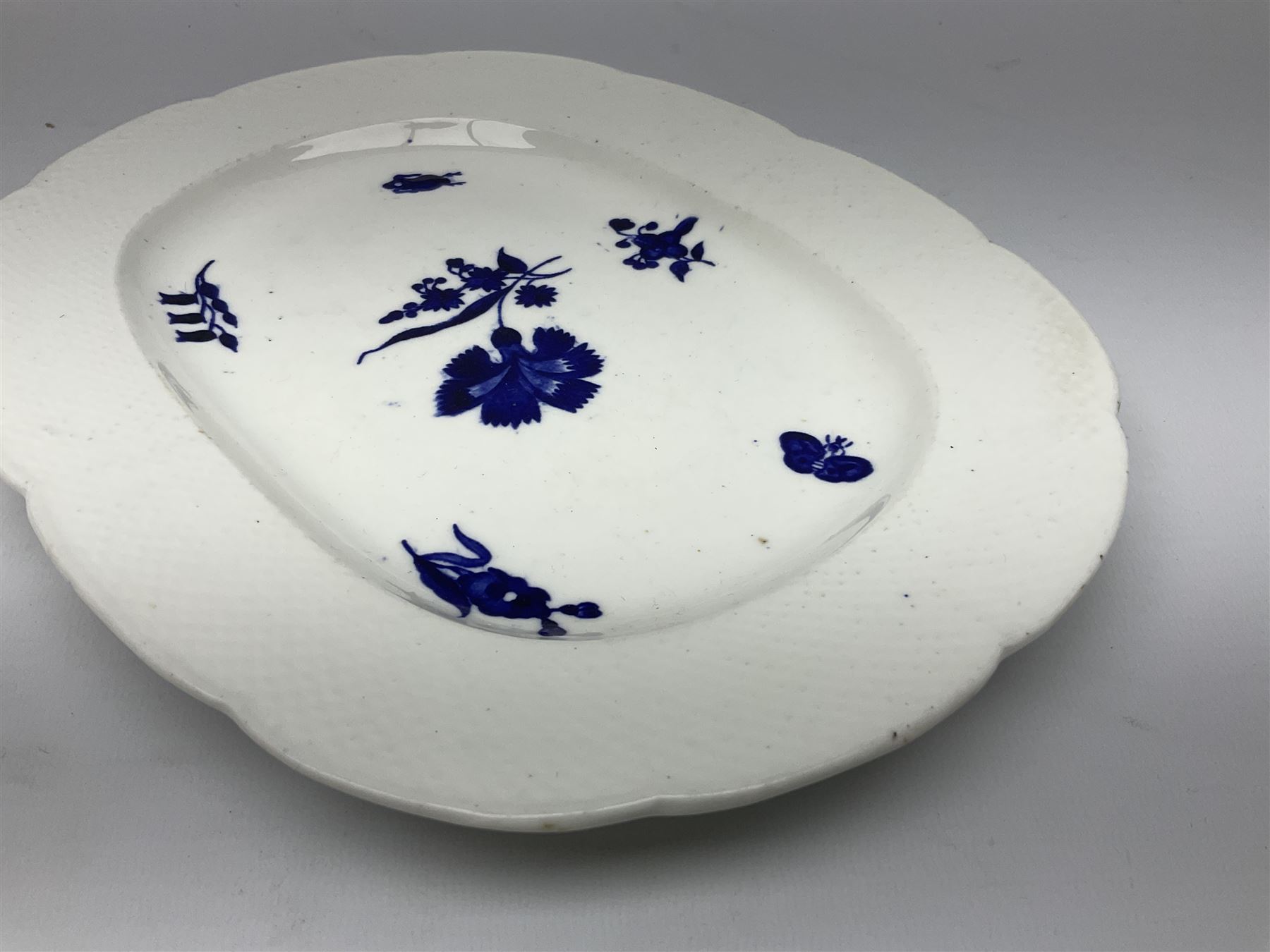 Three 19th century plates, comprising two circular examples and one oblong, each with osier moulded sides, the centres decorated in underglaze blue with Gillyflower type pattern, circular examples D25cm oblong example W27cm