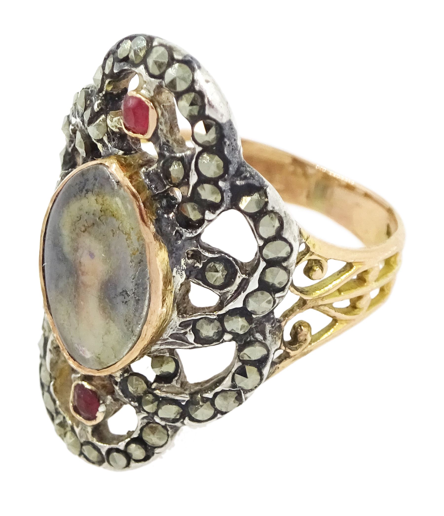 19th century gold and silver marcasite portrait ring, set with an oval miniature of a woman on ivory, under a glazed panel, with a marcasite and red stone set crossover surround, with pierced gold shoulders and reeded shank. This lot has been registered for sale under Section 10 of the APHA Ivory Act