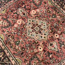 Persian pale red ground rug, the field decorated with flower heads, repeating guarded border, 117cm x 106cm
