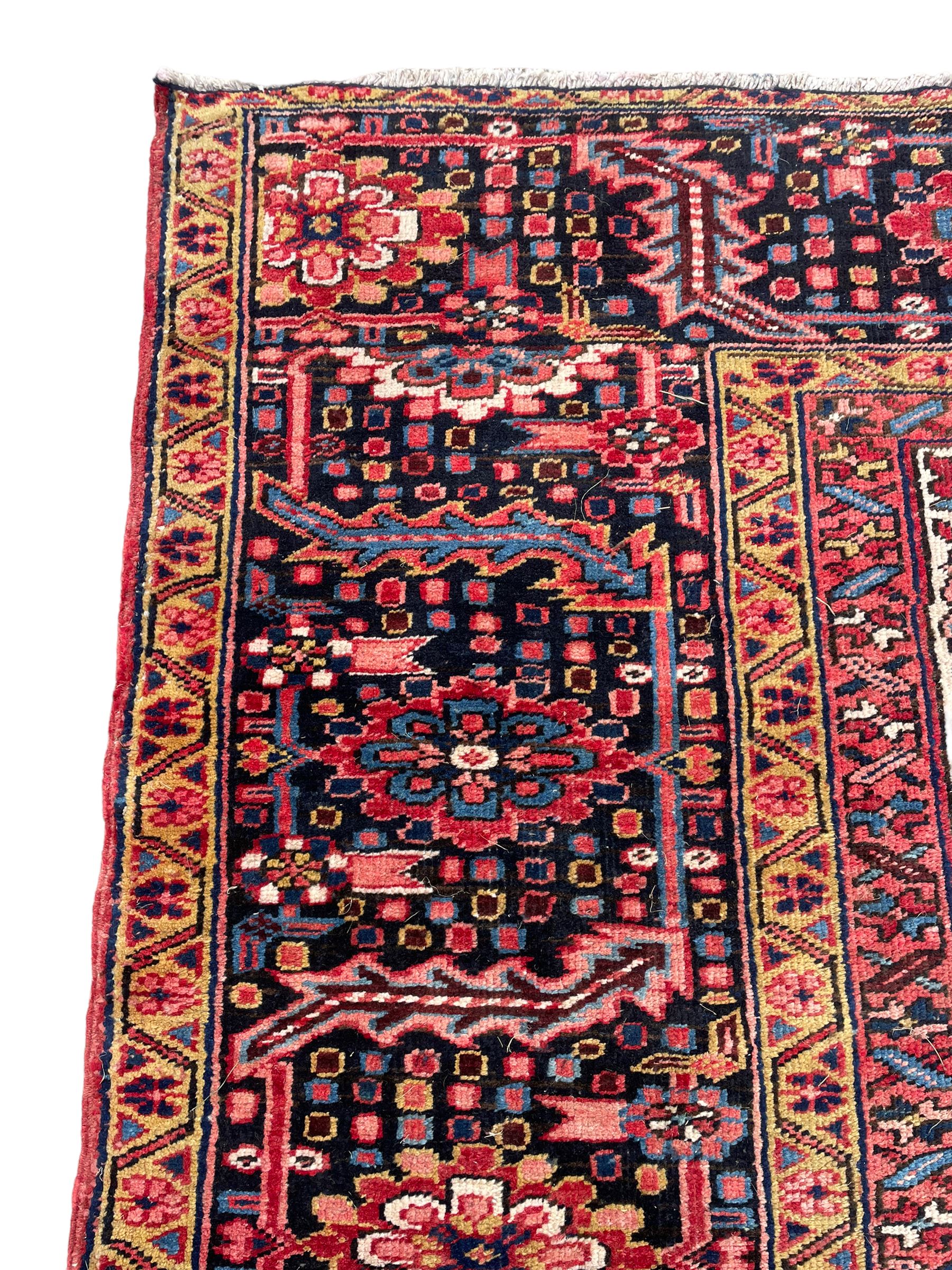 Antique Persian coral ground carpet, the large central floral pole medallion with extending foliate designs, the thick guarded indigo border with repeating flower heads and circles