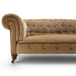 Victorian mahogany framed two seater Chesterfield settee, traditional shape with rolled back and arms over sprung seat, upholstered in buttoned-back neutral fabric, raised on turned front supports with ceramic castors