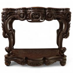 Chinese stained hardwood side table, late Qing dynasty style, with shaped top above a pierced and carved frieze of foliage and fruiting vines, cabriole legs terminating in scroll feet, united by a carved shaped undertier