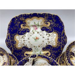 19th century porcelain part tea service, comprising twelve teacups, ten coffee cups, eleven saucers, slop bowl, and cake plate, decorated in the manner of Ridgeway or Alcock, hand painted with floral sprigs within a blue shaped border, and heightened in gilt with C scrolls and foliate detail, with painted pattern number 5954 beneath 