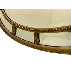 19th/20th century oval gilt framed mirror, set with bevel plate panes, foliate moulded outer band and bead moulded inner band, with Adam style cartouche mounts