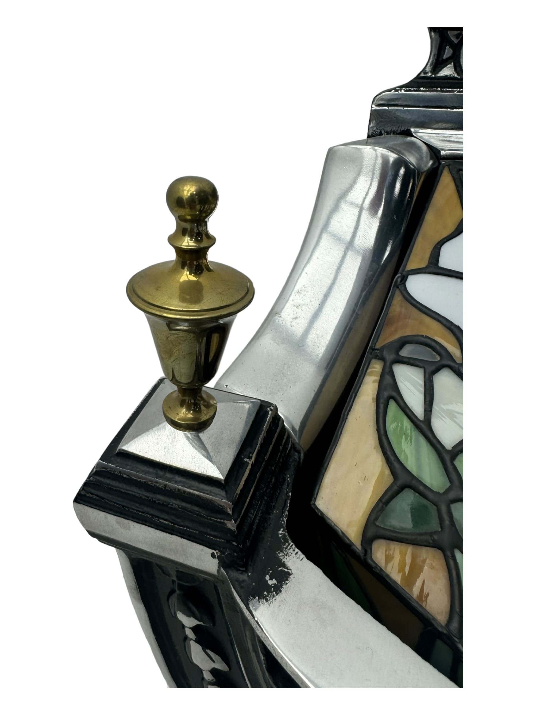 Stained glass and cast iron electric fireplace, arched top with decorative finials, stained glass front panel with floral motifs, flanked by cast iron scrolls, raised on scroll supports