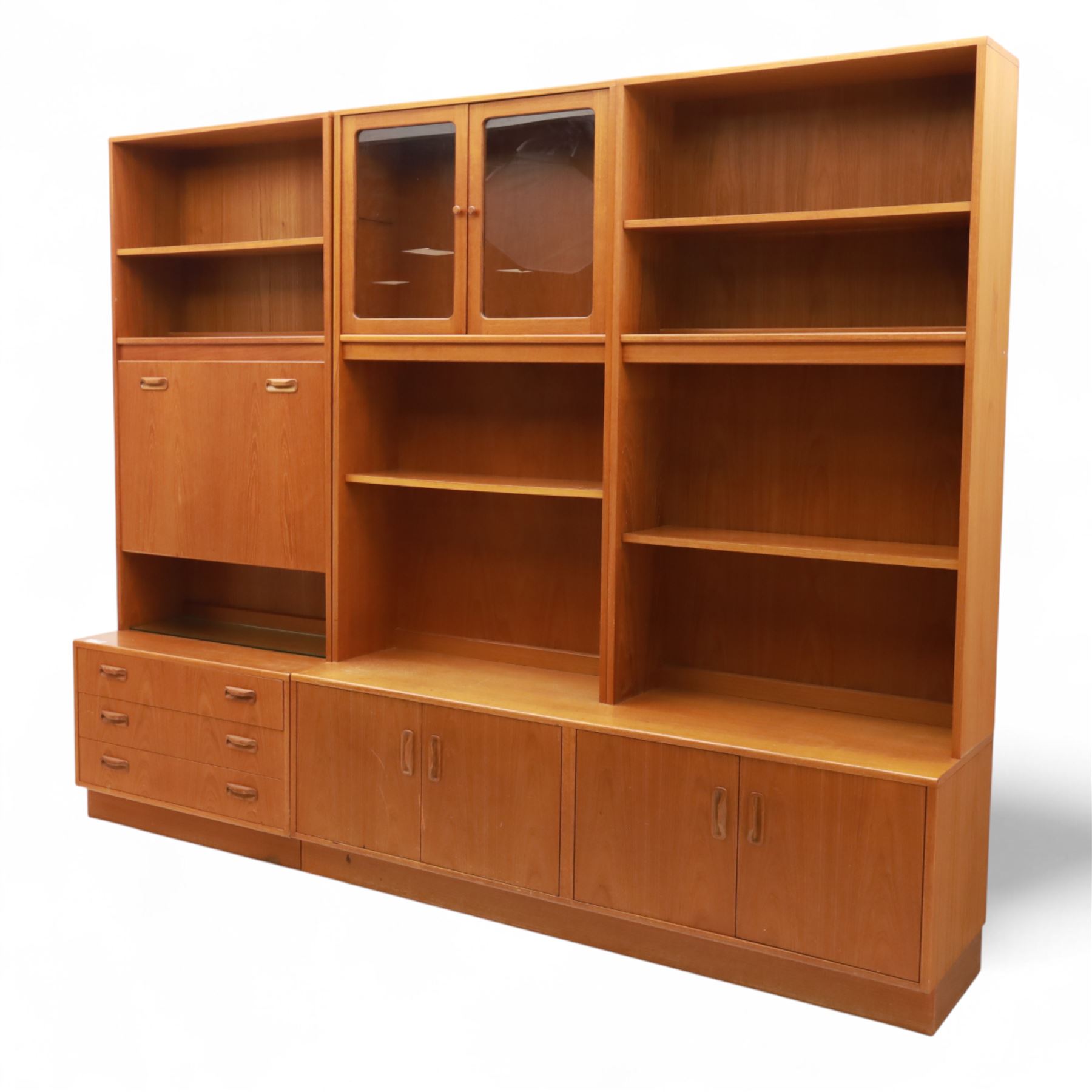 G Plan - Mid 20th century teak sectional wall cabinet, comprising six modular units including a fall front bureau, glazed display cabinet, open bookcase, cupboard and drawer bases, each with recessed handles and flush plinths