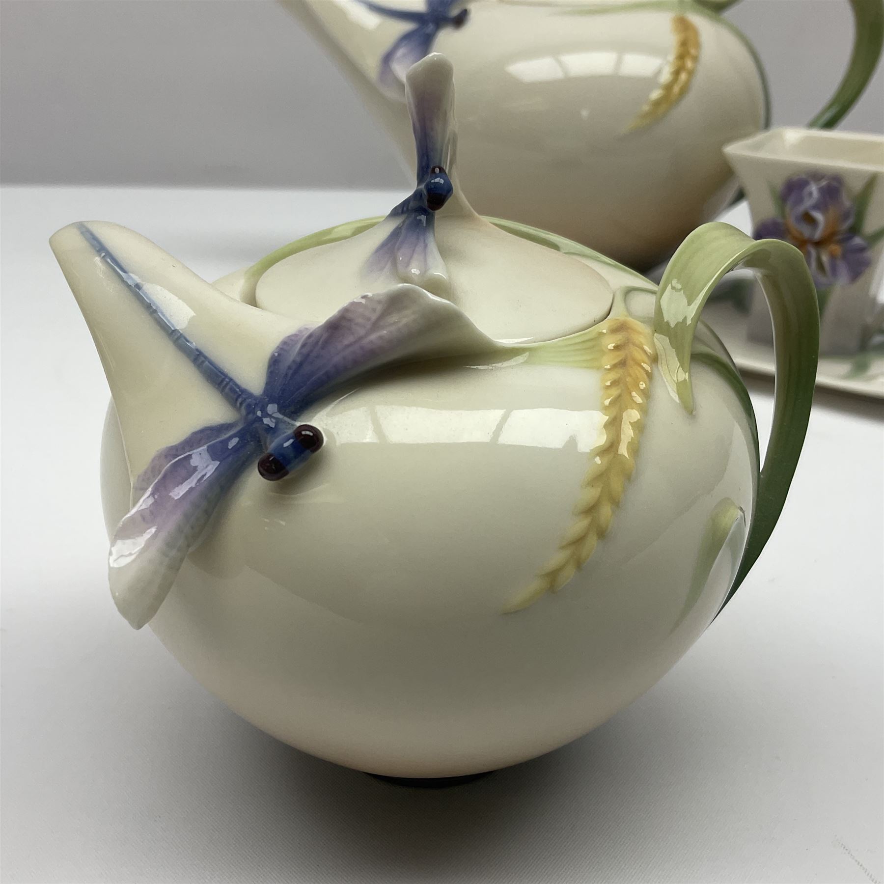 Franz Teapot decorated with dragonflies, together with a matching sucrier and cover and a cup and saucer in Iris pattern, all with printed mark beneath 