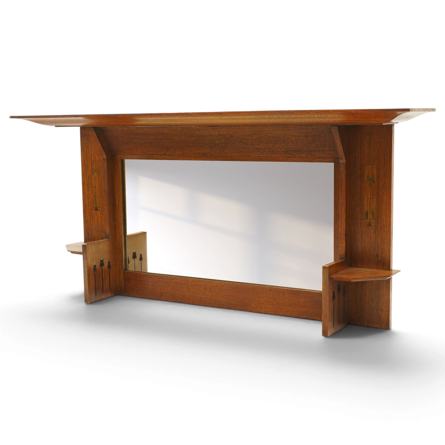 Manner of Liberty & Co, - Arts & Crafts inlaid oak overmantel mirror, the deep-projecting cornice over a rectangular plate, flanked by Art Nouveau marquetry panels of stylised tulip and foliate motifs, over a canted shelf and tulip-pierced upright