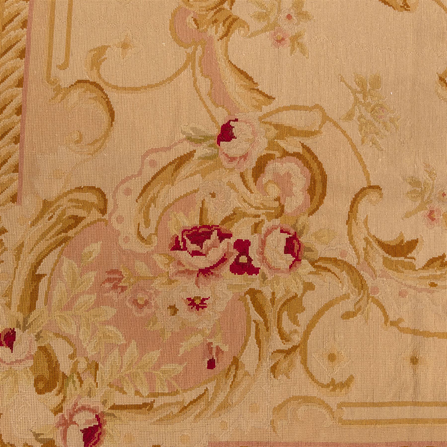 20th-century Aubusson-style tapestry wall hanging of square form, woven with a central floral medallion composed of delicate sprays in soft pinks, creams, and muted greens, framed by scrolling acanthus ornamentation and floral cartouches to each corner, all set within a pale ivory ground and enclosed by a terracotta toned border 