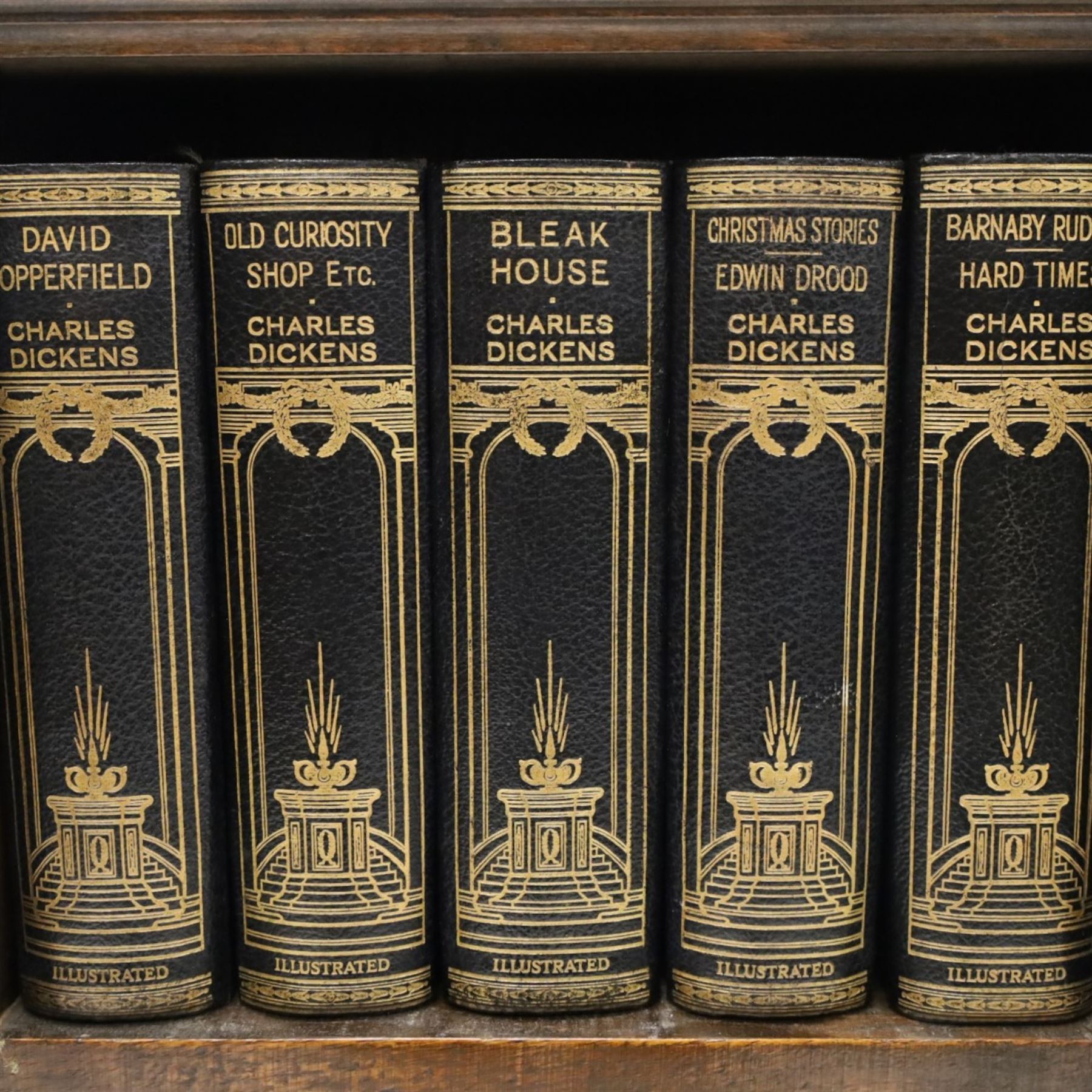 Small Edwardian mahogany open bookcase with Charles Dickens books, oak bookcase with galleried top, containing fifteen hardback books  