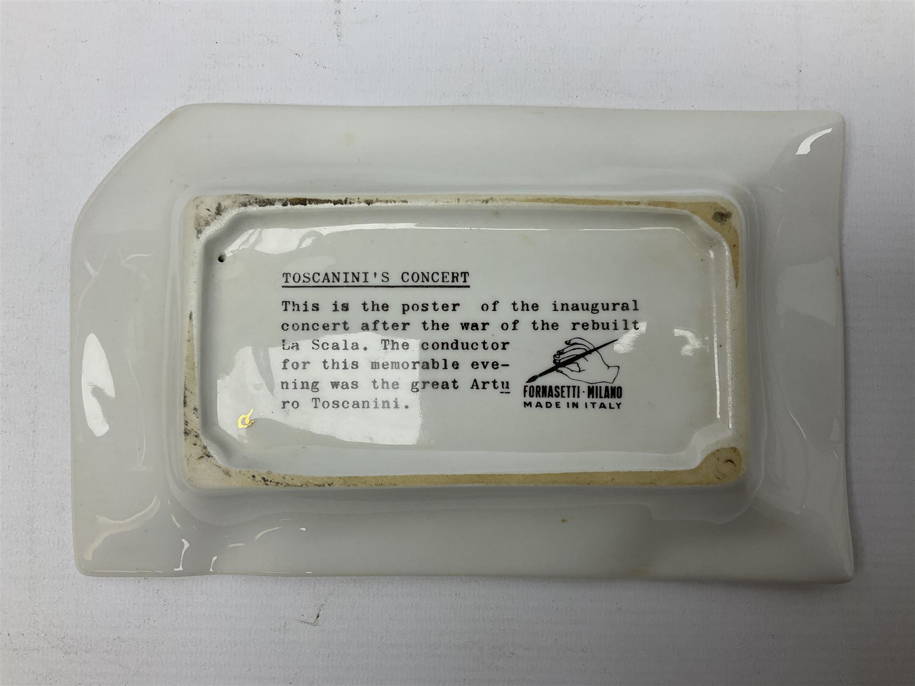 Fornasetti rectangular 'Toscanni's Concert' poster ashtray decorated with black and white text with a gilt border edge, with printed mark beneath, H22cm 