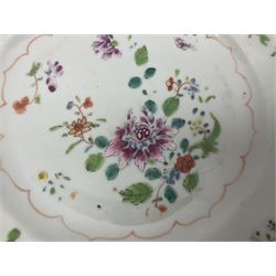 Three 18th century Chinese Famille Rose plates, the first example enamelled with blossoming peonies, rockwork and fence, the other two examples of similar design, decorated with blossoming peonies and sprigs within shaped inner borders, each approximately D23cm
