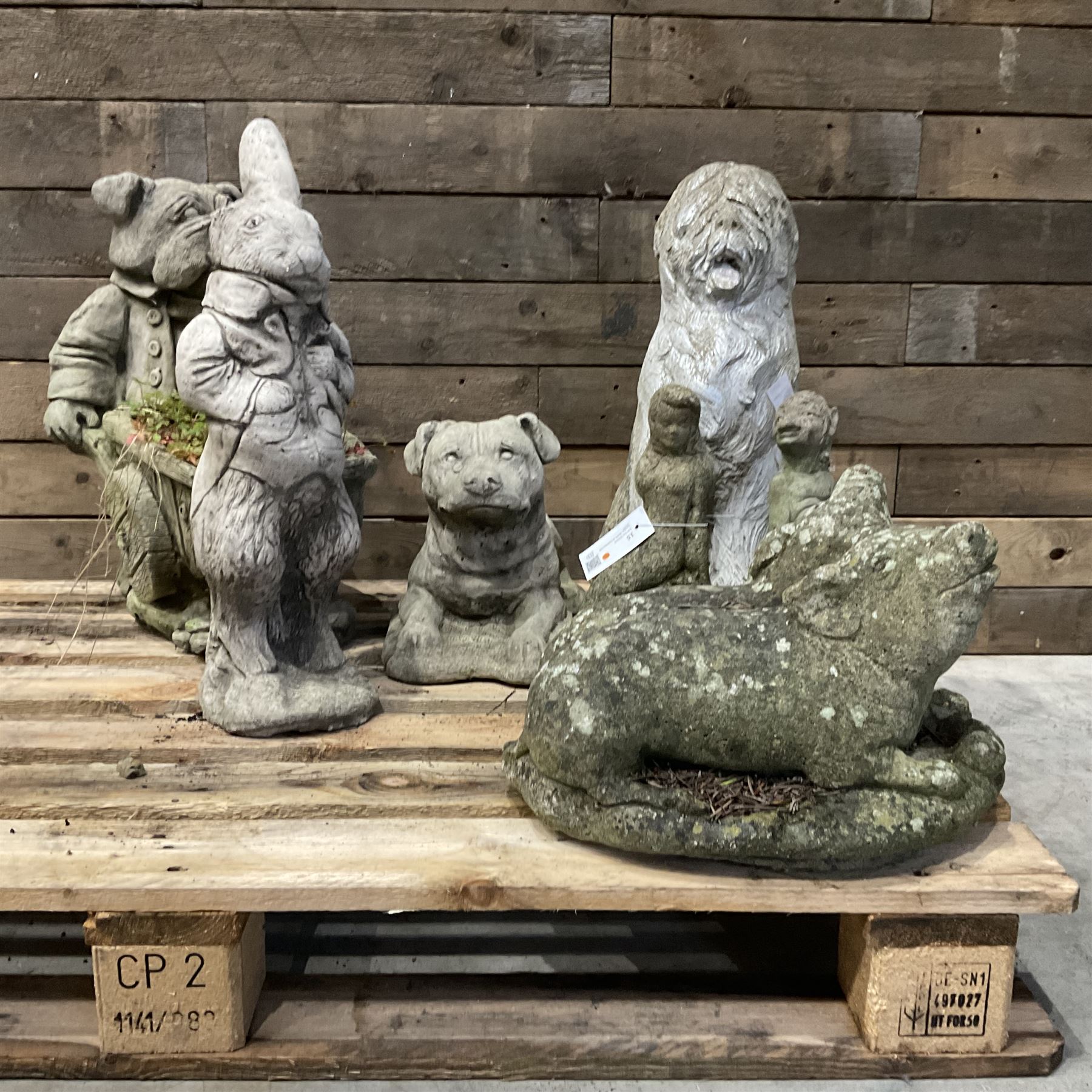 Various cast stone and composite garden ornaments, to include Peter Rabbit, goose, pigs, dogs, dog with wheelbarrow, painted metal bird bath and other, on two pallets