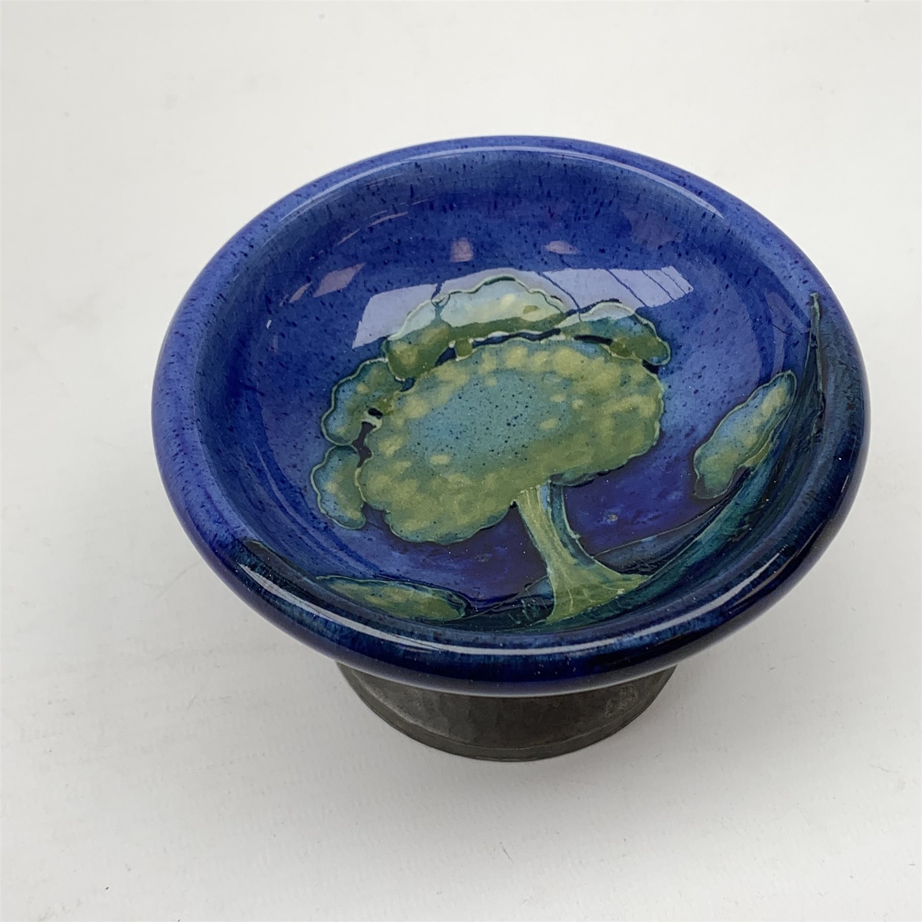 William Moorcroft for Liberty & Co, small pedestal dish, the shallow bowl decorated in the Moonlit Blue pattern, raised upon a Tudric pewter base, impressed beneath Made in England, Tudric Moorcroft 01339, H7cm, D11cm