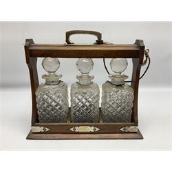 Edwardian oak tantalus with silver plated mounts with three square sided glass decanters, complete with key